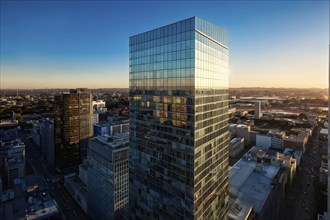 Office building with a full glass facade at golden hour, AI generated