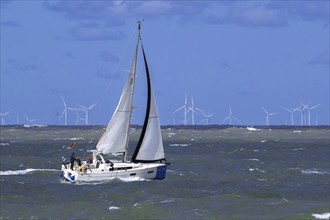 Sailboat sailing along wind turbines of wind farm Borssele in the North Sea at Westkapelle,