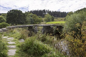 The old Postbridge Clapper Bridge crosses the East Dart River in Dartmoor National Park near