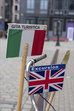 Signs with Italian and English flags show tourists which city tour is taking place in which