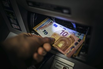 Symbol photo on the subject of withdrawing money from an ATM. Banknotes being withdrawn from an ATM