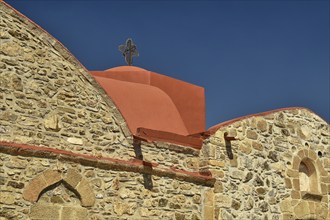 Historic church with stone façade and red roof under a clear blue sky, Asklipio village, Asklipion,