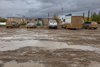 Dirty cars and muddy car park in front of pub, adventure tourism, Dalton Highway, Alaska, USA,