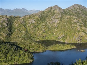 Lonely red cabin at lake near Mt. Sukkertoppen, the mountain next to Hamn i Senja, Senaj island,