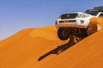 A Toyota Landcruiser crosses a sand dune in the Rub al Khali desert, Dhofar province, Arabian