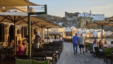 People sitting on a terrace of a restaurant enjoying the view at sunset while eating, Mandraki,