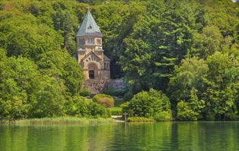 Votive chapel Memorial Chapel of St Ludwig on the lakeshore with wooden cross in the lake, the