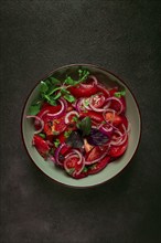 Fresh tomato salad, with red onion, spices and herbs, top view, close-up, homemade