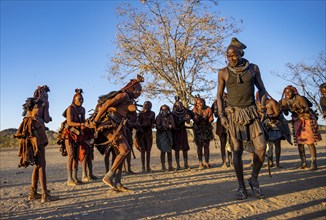 Group of traditional Himba woman with chief of the village standing in a semicircle, clapping and