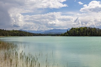 Still lake with a view of the surrounding mountains under a vast cloudy sky, Osterseen