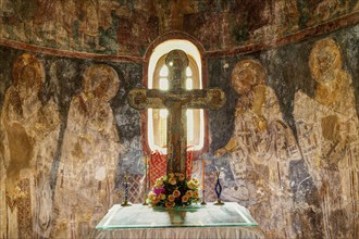 HDR, View of an altar with a cross, flowers and religious wall paintings in the background,