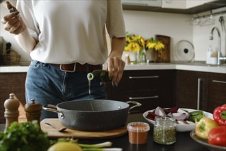 Unrecognizable woman pouring olive oil in an oven pan from bottle