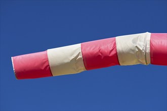 A red and white windsock blows against a clear blue sky, Germany, Europe