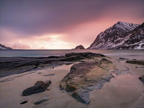 Rocks on Haukland beach in the evening light, snow-capped mountains in the background, Vestvågøya,