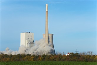 Large cloud of dust envelops an industrial plant in autumnal surroundings under a blue sky,