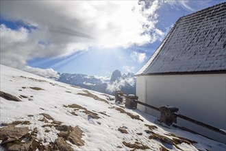 Snowy landscape with house and sunshine over the mountains