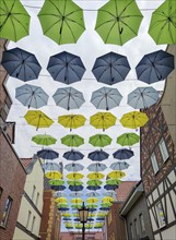 A street decorated with colourful umbrellas under a cloudy sky, Münsterland, North