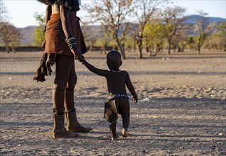 Traditional Himba woman holding a small child by the hand, near Opuwo, Kaokoveld, Kunene, Namibia,