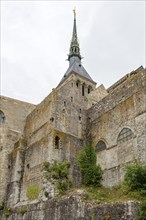 A Gothic stone church tower rises majestically into the cloudy sky, Le Mont-Saint-Michel