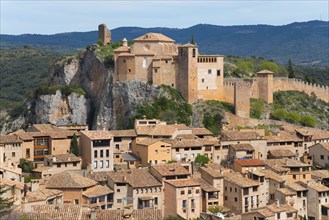 Historic castle perched above stone houses in a medieval village on a rock, collegiate church on