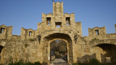 Ancient stone ruins of an arch under a clear blue sky, Tor tor of St Paul, harbour area, Rhodes