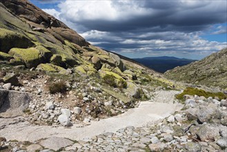 A stony path in a rocky mountain landscape under a cloudy sky, hiking area, Reserva national de