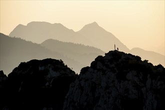 Lone mountaineer on the summit of the Hörndlwand in the Chiemgau Alps with the silhouette of