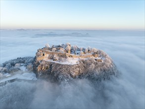 Aerial view of the Hegau volcano Hohentwiel with Germany's largest fortress ruins on a cold, foggy