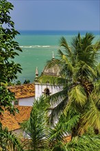 Baroque church tower hidden between vegetation and the sea in the historic city of Olinda in