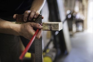 A man marks a section on a piece of wood with a square and pencil. Berlin, 14.08.2024