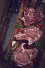 Raw calf meat, meat on the bone, meat for barbecue, cutting board, with spices and herbs, top view