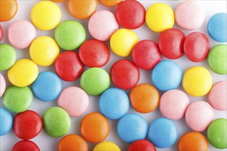 Colorful multicolored chocolate candy dragees on white background. Top view, close up