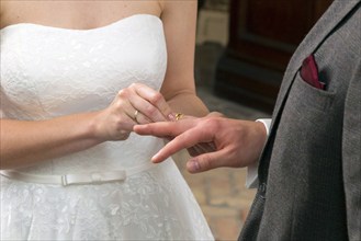 The bride slips the wedding ring over the groom's ring finger during the wedding ceremony,