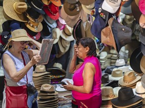 Oaxaca, Mexico, A woman sells a hat to a tourist at the Benito Juarez Market. Opened in 1894, it is