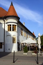 Historic building with a pointed roof and an outdoor terrace on a cobbled street, town hall,