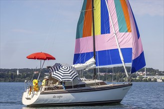 Sailing party on Lake Constance, yacht with colourful foresail and sunshades, Immenstaad,