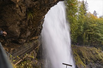 An impressive waterfall under a rock overhang in autumn forest, Lake Brienz, Switzerland, Europe