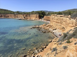 Small beach with clear waters surrounded by high cliffs and rocks at Playa es Bol Nou, Sa Caleta,