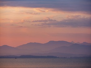 Small sailing boat on the Chiemsee in the morning light, behind the Chiemgau Alps, Chiemgau, Upper