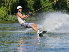 Young man with wakeboard in lake, water sports, water skiing in wakepark