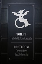 Sign for disabled toilet with wheelchair symbol on black background, Tivoli Amusement and