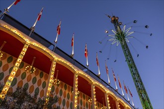 Building with illuminated Danish flags and Star Flyer chain carousel with passengers at high