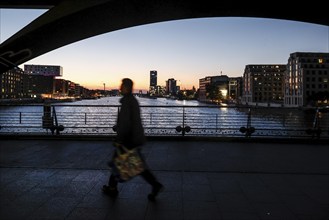 Pedestrian to the sunrise at the Oberbaum Bridge, view through the arcades over the Sprees to the