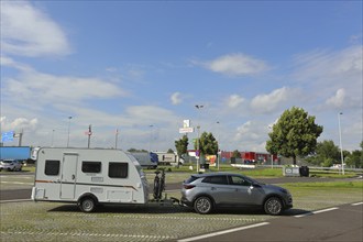 Car with caravan standing on a motorway service area, Tank und Rast, Caravan, service area near