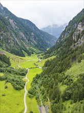 A lush green valley with a road and steep mountains covered in lush forests, Stilluptal, Austria,