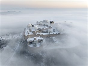 Aerial view of the Hegau volcano Hohentwiel with Germany's largest fortress ruins on a cold, foggy