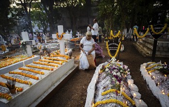 People from Christian community light candles and offer prayers on the grave of their relative