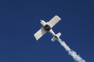 Stunt aerobatic plane inverted flying performing stunts in blue sky. Concept of speed, difficulty,