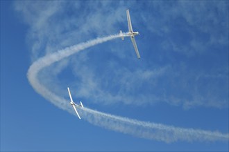 Stunt aerobatic plane performing stunts in blue sky with smoke trail. Concept of teamwork,