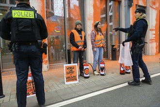 Police officer confiscates Last Generation banner after colour attack on Total Energies building.